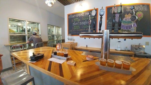 A bar with a wooden top and tap handles. Chalkboards listing their offerings hand on the wall.