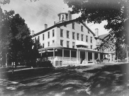 A black and white historic images of the Inn shows the exterior of the building from a street view. 