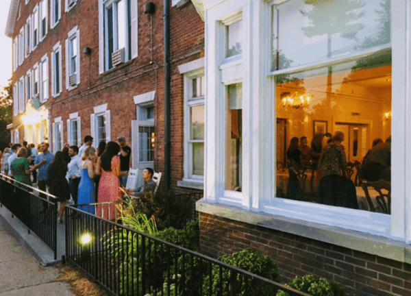 The outside of the Inn shoes a gathering of people on the porch.